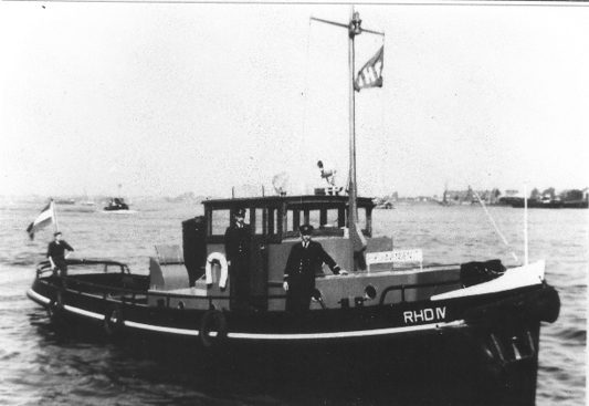 De RHD IV varend met twee mannen in uniform aan dek